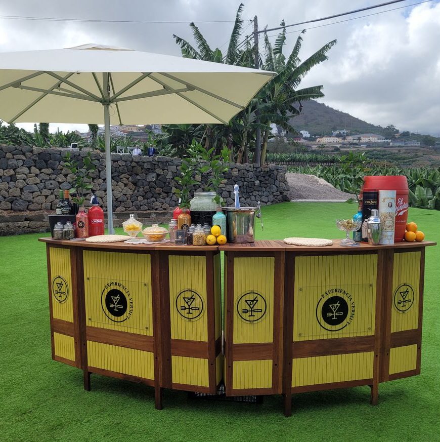 Una pequeña barra de bar montada sobre cesped en un evento privado